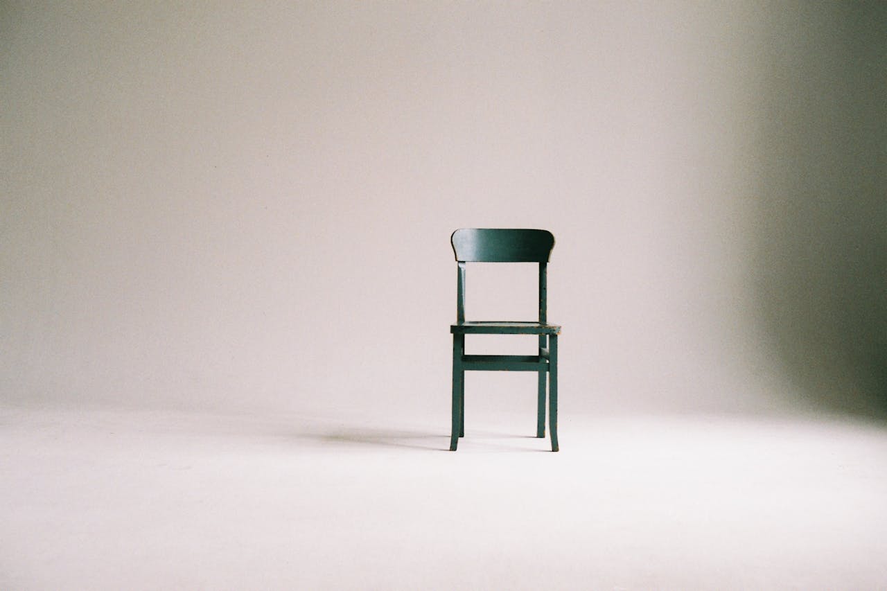 A single black chair in a minimalistic studio setting with a neutral backdrop.